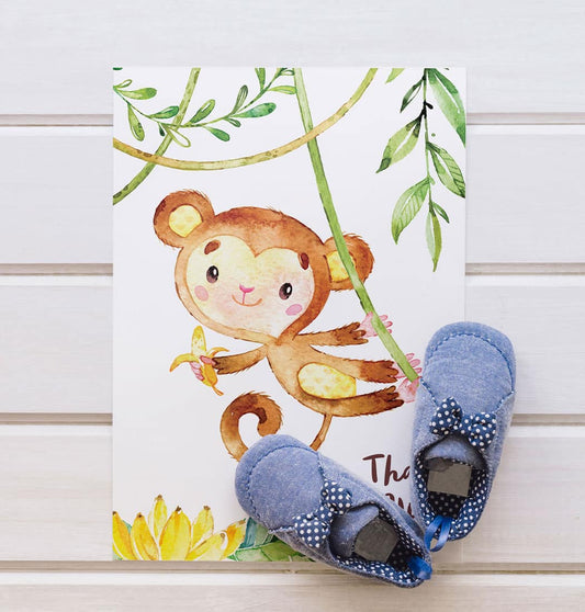 Blue baby shoes placed on top of a greeting card with cute baby monkey
